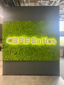 CBRE Baltics kontori mätassamblikust sein valgustatud logoga. Akustiline sein.