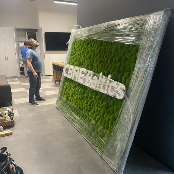 CBRE Baltics kontori mätassamblikust sein valgustatud logoga. Akustiline sein.