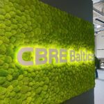 CBRE Baltics kontori mätassamblikust sein valgustatud logoga. Akustiline sein.
