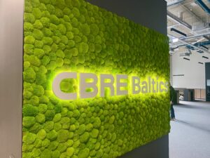 CBRE Baltics kontori mätassamblikust sein valgustatud logoga. Akustiline sein.