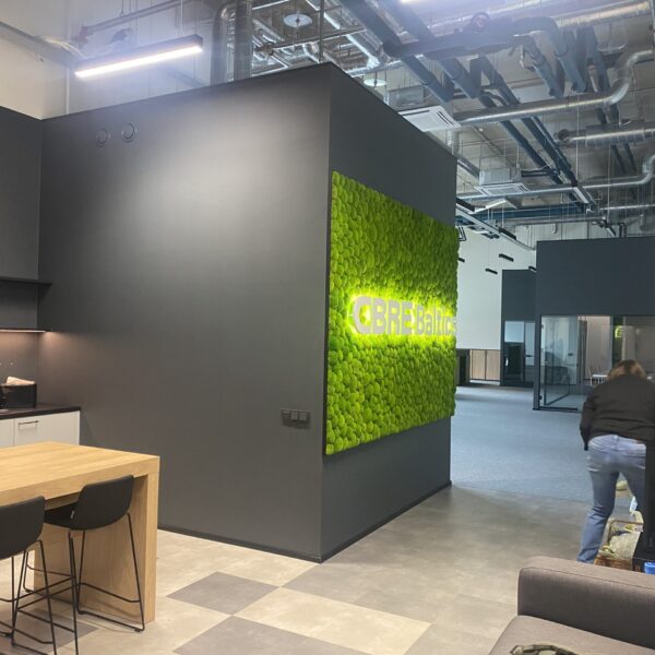 CBRE Baltics kontori mätassamblikust sein valgustatud logoga. Akustiline sein.