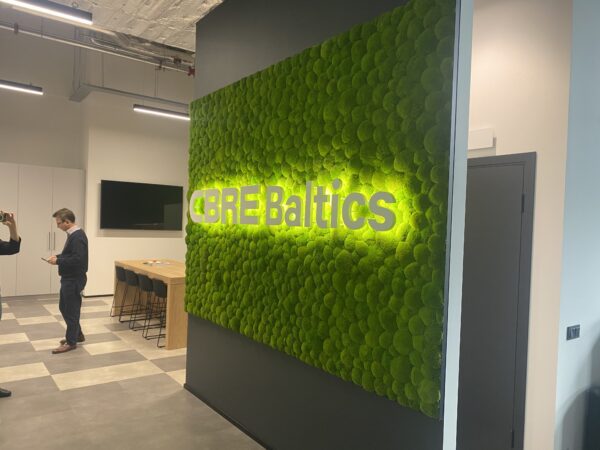 CBRE Baltics kontori mätassamblikust sein valgustatud logoga. Akustiline sein.