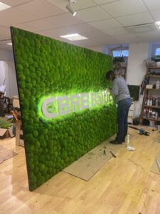 CBRE Baltics kontori mätassamblikust sein valgustatud logoga. Akustiline sein.